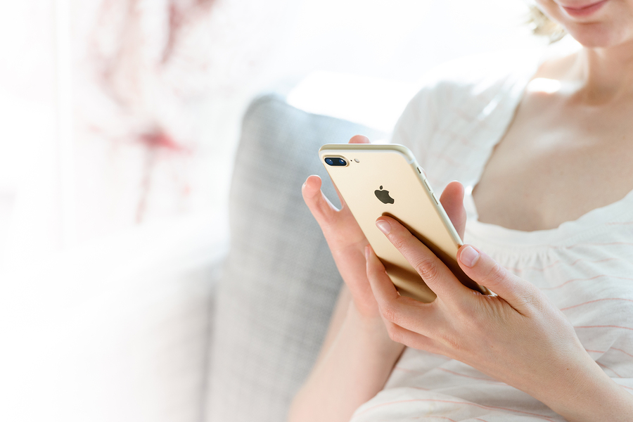 PARIS FRANCE - SEP 29 2016: New Apple iPhone 7 plus display in woman's hands - she is testing the camera and overall presentation sitting on the couch in home environment. New Apple iPhone tends to become one of the most popular smart phones in the world