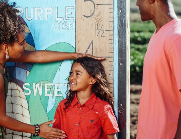 ARFID Family enjoys a sunny day measuring child's height at a corn field.