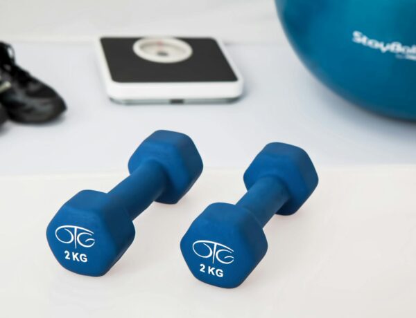 Blue dumbbells placed on a white surface with fitness equipment in the background.